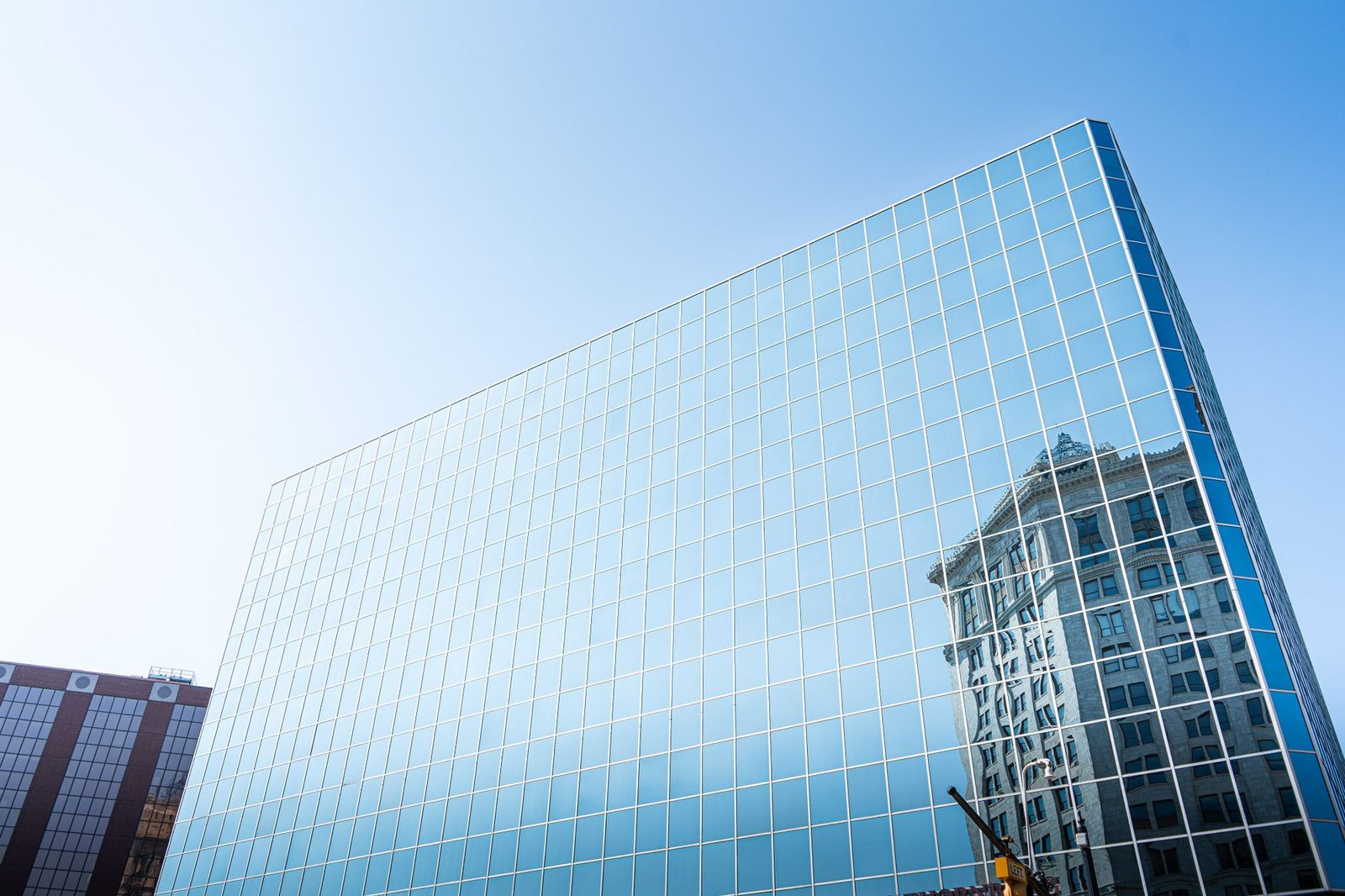 A modern glass skyscraper reflecting the historic McKay Tower in downtown Grand Rapids, Michigan.